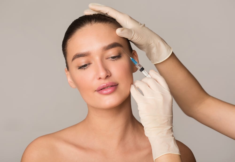 Young woman receiving Botox injection for wrinkle reduction, illustrating cosmetic surgery and beauty enhancement procedure.