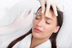 Young woman receiving a Bio-Filler injection to her forehead from a professional cosmetologist, enhancing skin rejuvenation and reducing fine lines naturally