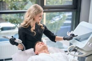 Experienced cosmetologist adjusting radiofrequency energy levels during a microneedle RF lifting treatment for skin rejuvenation